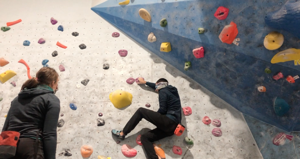 John is on a climbing wall. His foot is close to the hold he needs.